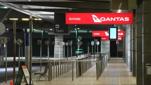 James D. Morgan An empty airport below a sign saying "Qantas arrivals"