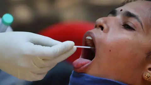Getty Images A doctor takes a swab sample of a resident at a Covid-19 coronavirus testing drive inside the Dharavi slums