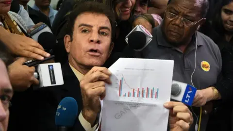 AFP The presidential candidate for Honduras" Opposition Alliance against the Dictatorship, Salvador Nasralla (centre L), gestures as he meets with coordinator of the Electoral Supreme Tribunal, Leticia Henriquez (not pictured), to present a document asking to annul the results of the still-unresolved November 26 vote