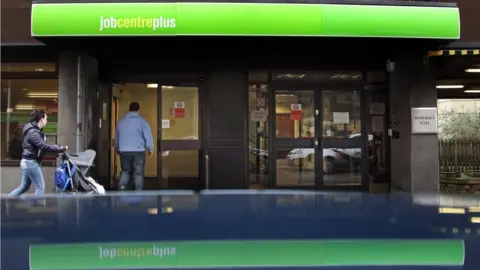 Getty Images woman with pushchair and man walking into a job centre