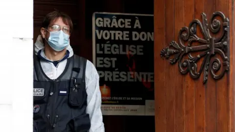 EPA A masked police officer looks out from the doorway of the Notre Dame church in France