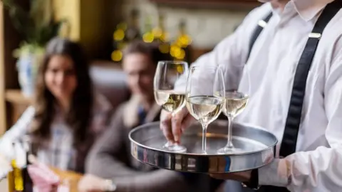 Getty Images A waiter serving glasses of wine