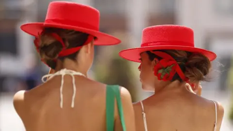 Shutterstock Two women wear hats to protect themselves from the sun in Malaga
