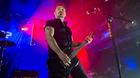 Carrie Davenport/Getty Images Andy Cairns playing the guitar