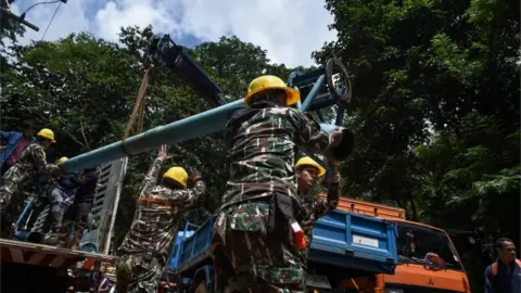 AFP/Getty Technicians lifting water pumps at drilling site near the cave system