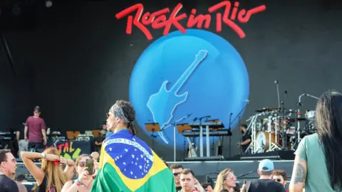 Getty Images Man wrapped in Brazilian flag in front of a stage at Rock in Rio.