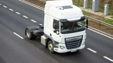 NAtional Highways White HGV cab in lane 2 of a motorway, seen from a bridge