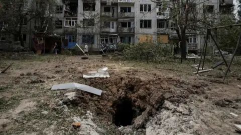 Reuters Local residents walk in front of an apartment building destroyed in a missile strike, amid Russia's invasion of Ukraine, in Bakhmut on 13 June