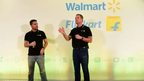Getty Images Walmart CEO Doug McMillon (R) speaking next to Flipkart co-founder and CEO Binny Bansal at an event in Bangalore