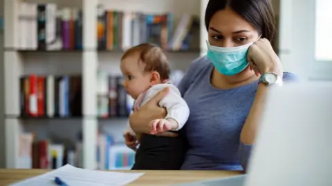 Getty Images Woman with baby looks at computer