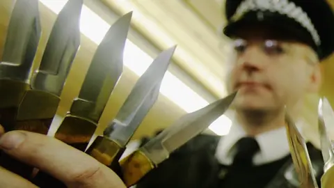 Getty Images An officer holds knives handed in to police