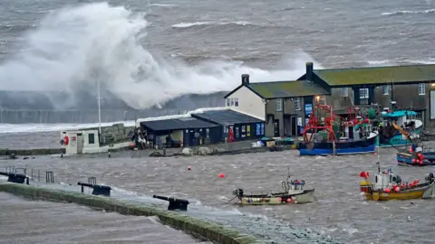 PA Media Waves crash over the sea wall at the harbour in Lyme Regis in Dorset as Storm Eunice hits the south coast on 18 February 2022