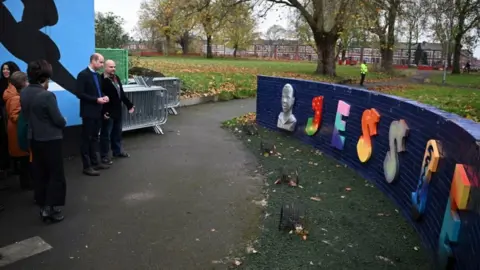 Oli Scarff/PA The Prince of Wales looks at Jessie's Wall, a memorial built in tribute of Jessie James, a teenager shot dead in 2006 in a park in Moss Side,