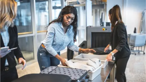 Getty Images Woman waiting at airport to have her bags searched