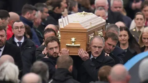 PA Media Mourners carrying the coffin of Martin McGill outside St Michael's Church, Creeslough, following his funeral