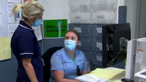 An ambulance navigator tells a nurse how many ambulances are waiting