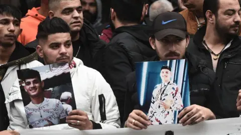 Getty Images Demonstrators hold images of the 16 year old killed in a police shooting