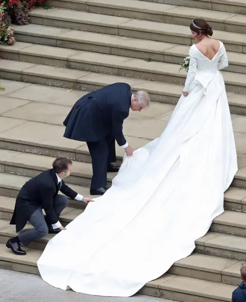 Getty Images Princess Eugenie of York receives help with her train from her father Prince Andrew