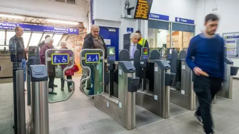 Northern People using ticket barriers at a railway station