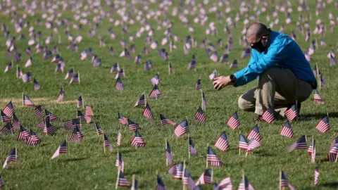 Getty Images Chris Duncan, whose 75 year old mother Constance died from Covid, seen at September memorial among small US flags to commemorate the Covid dead