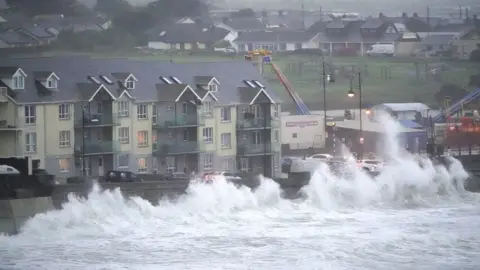 PA Media Waves crash against the sea wall in Tramore, south-east Ireland, on Friday evening