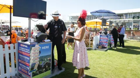 PA A racegoer places a bet at Goodwood Racecourse