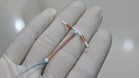 Getty Images A doctor holding an IUD birth control device to put into a patient's womb