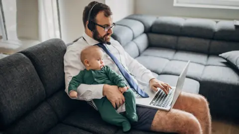 Getty Images Man working from home - holding a baby