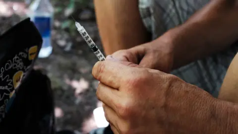 Getty Images A drug user (face unseen) holds a needle - Pennsylvania, July 2017