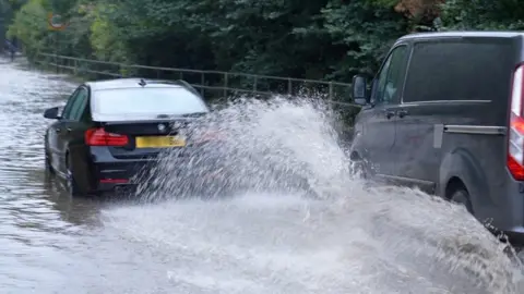 John Fairhall/BBC Car and van driving through flood