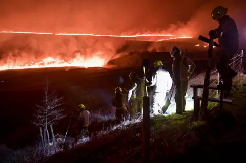 Getty Images Firefighters at moorland fire near Marsden