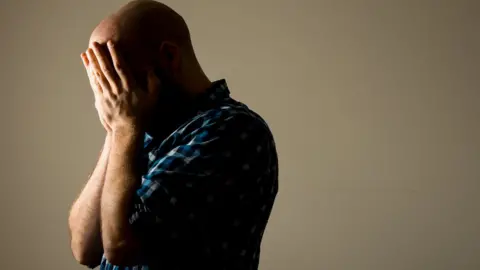 PA Media Man holds head in hands