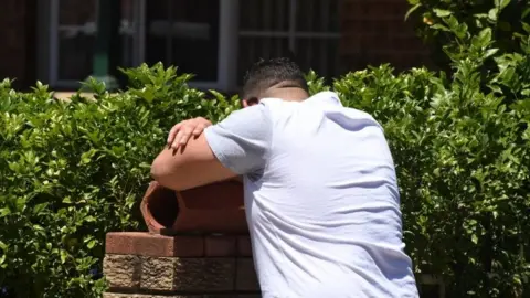 EPA A man with his head in his arms at the scene