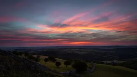 Dwayne Jones Sunset over a stone wall and trees