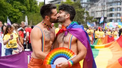 Getty Images Men kissing in front of a Pride flag