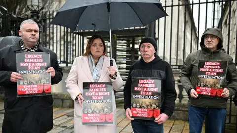 Getty/Charles McQuillan BELFAST, NORTHERN IRELAND - FEBRUARY 28: Supporters of Troubles victims hold placards outside the High Court ahead of the court ruling on February 28, 2024 in Belfast, Northern Ireland.
