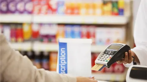 Getty Images Paying for drugs in a pharmacy