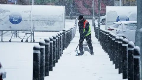 PA Media In nearby Hexham in Northumberland, a Tesco staff member battled the elements