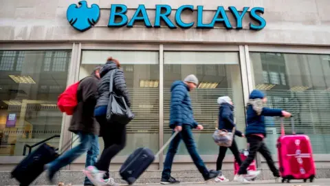 Getty Images Pedestrians walk past a branch of Barclays bank in central London