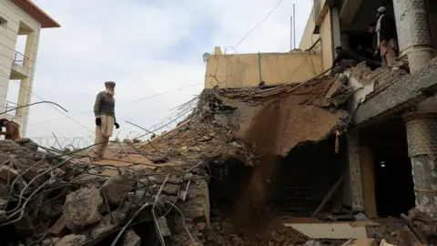 A man standing on rubble from the mosque