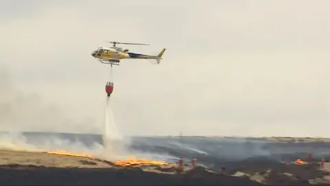 A helicopter drops water onto the fire