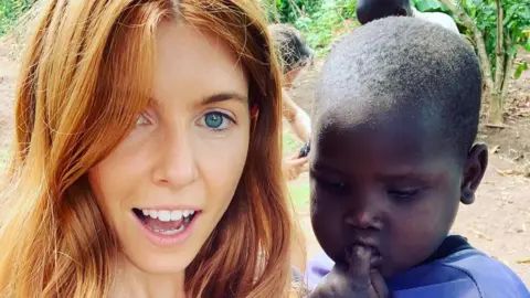 Stacey Dooley / Instagram Stacey Dooley in Uganda, posing with a young child