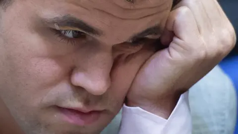 EPA Magnus Carlsen is seen in extreme close-up, hand resting on his cheek and staring intensely - perhaps even apprehensively - at the game board out of frame