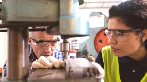 Getty Images Engineer and apprentice in factory