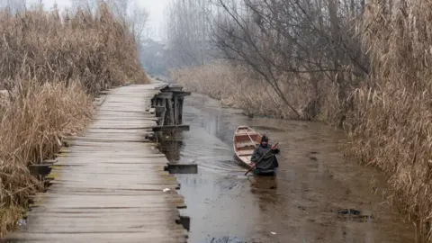 Getty Images A Boatman rows his boat on Dal Lake during a cold morning. A 40-day long period of harsh winter cold known locally as the 'Chillai Kalan' started on December 21 and should end on January 30. (Photo by Idrees Abbas/SOPA Images/LightRocket via Getty Images)