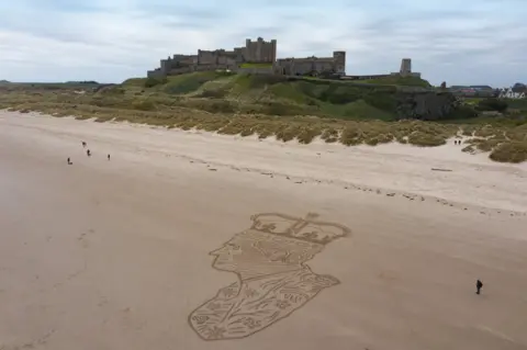 Claire Eason/Soul2Sand A large picture of King Charles drawn in sand next to a castle