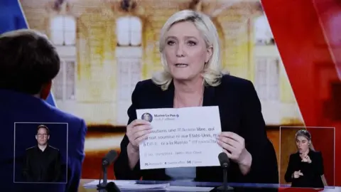Getty Images Marine Le Pen held up a printed tweet to prove her backing for a free Ukraine