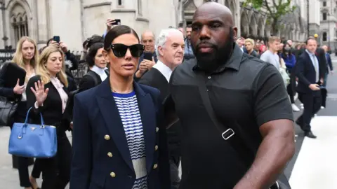 EPA Rebekah Vardy and her security guard at the High Court