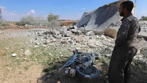 AFP A Syrian man stands near a destroyed house following a raid by Syrian government forces near the village of al-Muntar, in Hama province, on 8 September