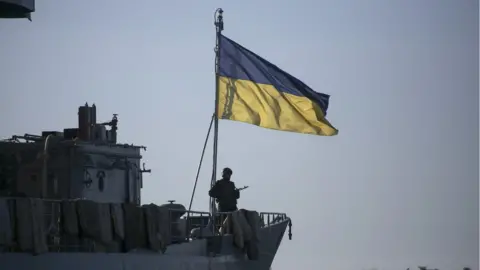 Reuters A Ukrainian naval ship, with a soldier standing in front of a Ukrainian flag